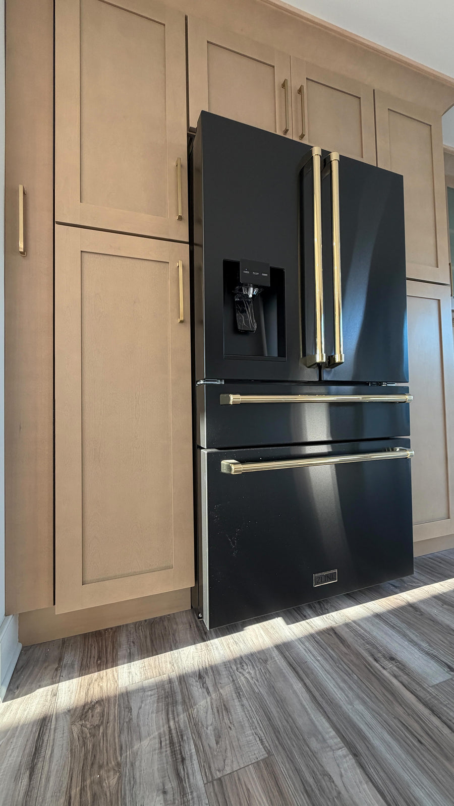 Natural wood tall cabinets with black and gold refrigerator